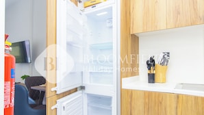 An open refrigerator with a wooden interior, a small table with a plant, and a chair. - Bloomfields Luxurious Stu Maryah Island (Abu Dhabi)