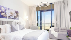 A modern hotel room with a large bed, a sofa, and a view of the city. - Bloomfields Luxurious Stu Maryah Island (Abu Dhabi)