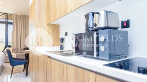 A modern kitchen with a coffee machine, a toaster, and a kettle on the counter. - Bloomfields Luxurious Stu Maryah Island (Abu Dhabi)