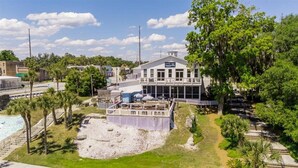 A riverside hotel with a pool, outdoor seating, and a large building with a sign.