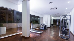 Un gimnasio moderno con equipo de ejercicio, ventanas amplias y piso de madera.