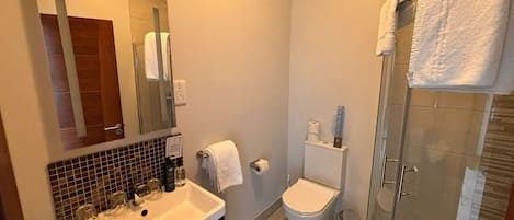 Un baño moderno con lavamanos, espejo, inodoro y ducha.