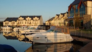 Un port esportiu amb diverses embarcacions amarrades, una filera de cases adossades i un edifici amb un rètol que diu "Hotel".