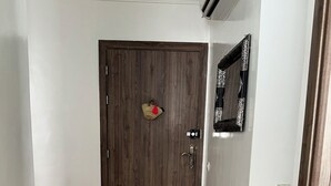 A hallway with a wooden door, a tiled floor, and a wall-mounted mirror.