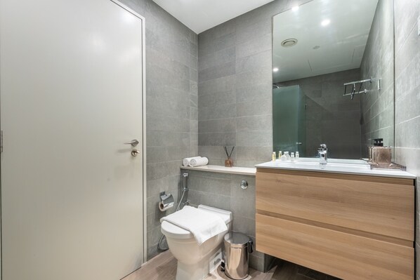 A modern bathroom with a toilet, sink, and shower.
