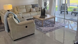 A spacious living room with a beige sofa, a coffee table, and a ceiling fan.