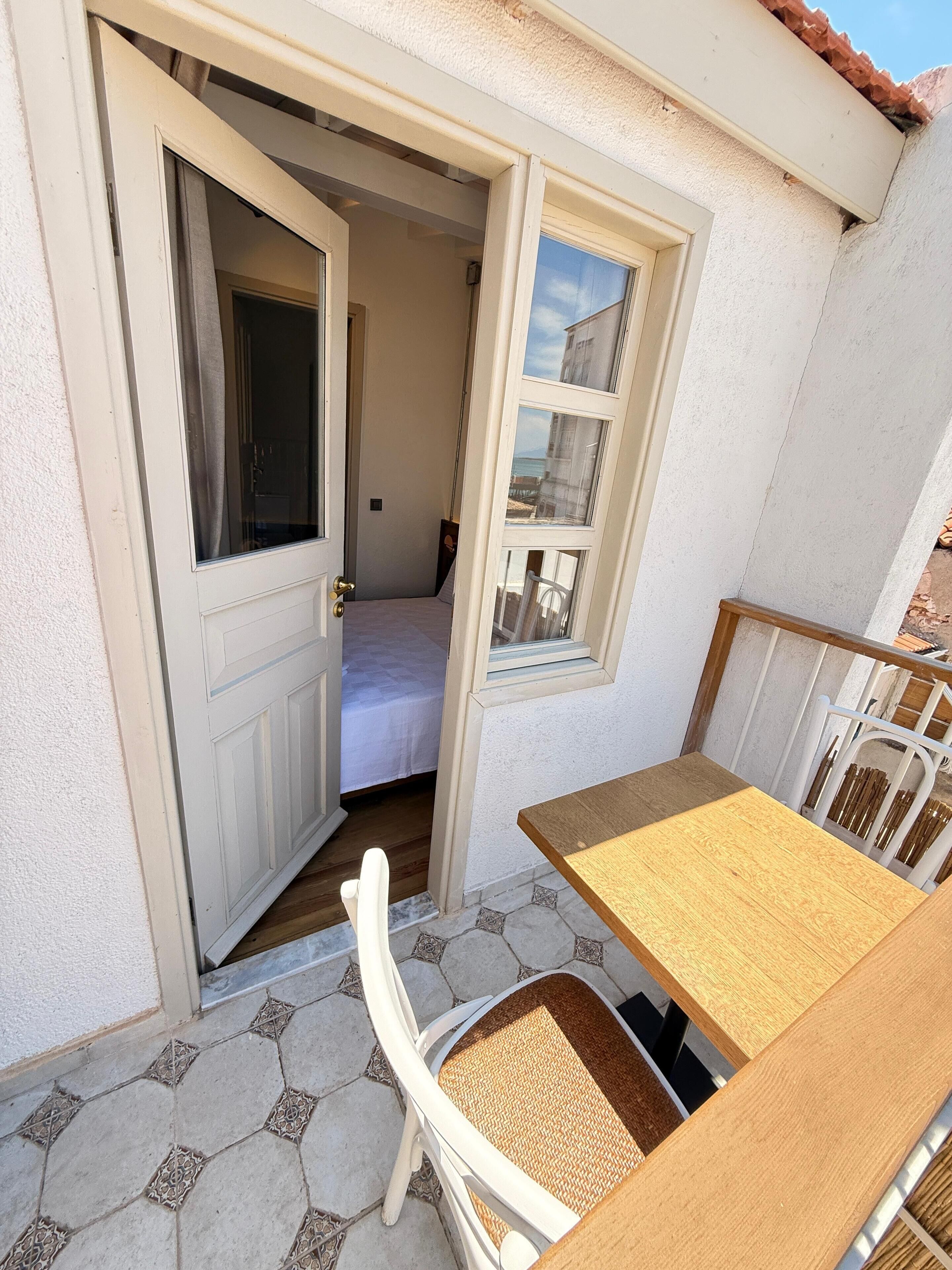 A small room with a bed, a window, and a table with a chair.