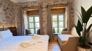 Un dormitorio con una cama grande, un sofá, una planta en maceta y una pared de piedra.