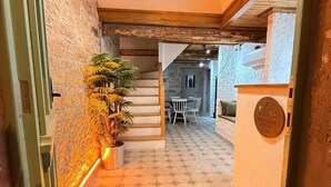 Entrada de un hotel con una escalera que lleva a un comedor, una lámpara decorativa colgante y un cartel que dice 'ELOS Boutique Hotel'.