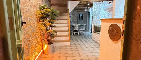 A hotel entrance with a staircase leading to a dining area, a decorative hanging light, and a sign for 'ELOS Boutique Hotel'.