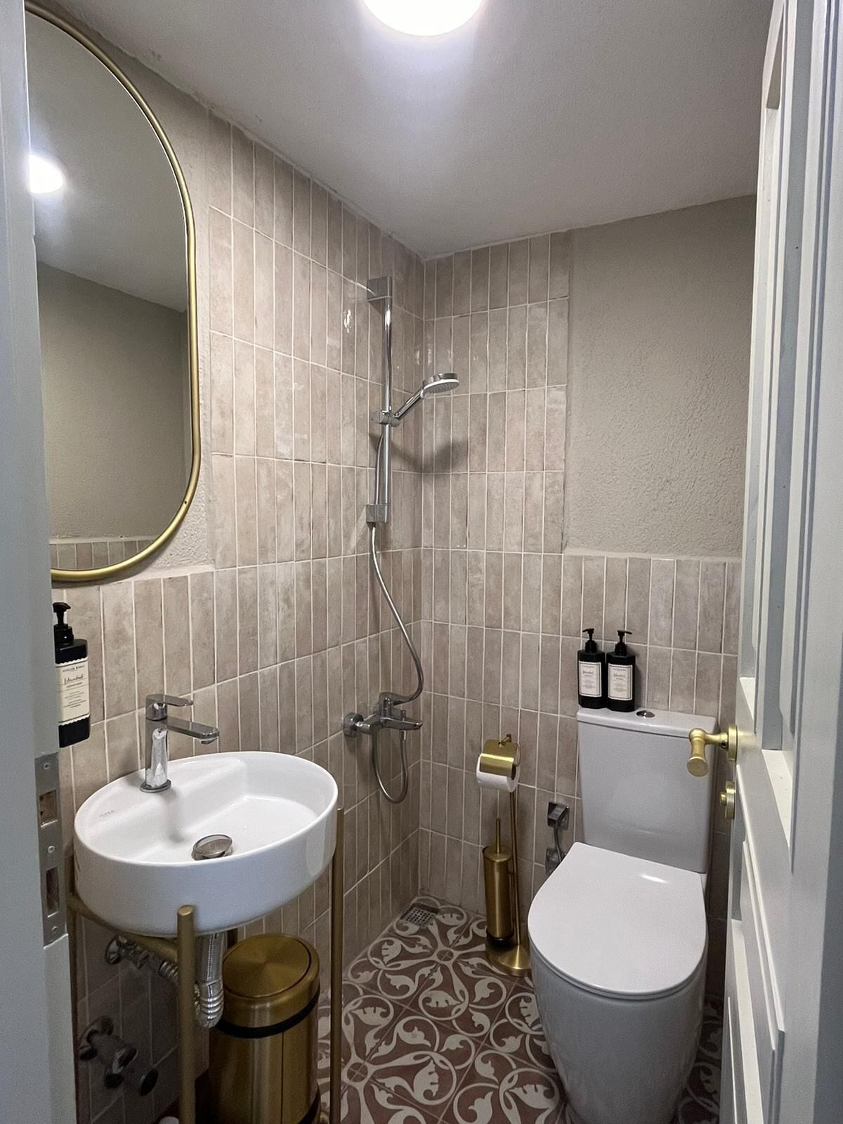 A compact bathroom with a white sink, a toilet, and a shower.