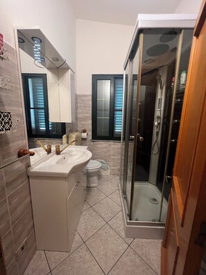 A modern bathroom with a glass-enclosed shower, a white sink, and a toilet.