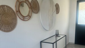 Um corredor com parede branca, mesa consola de metal preto e painéis de parede decorativos trançados.
