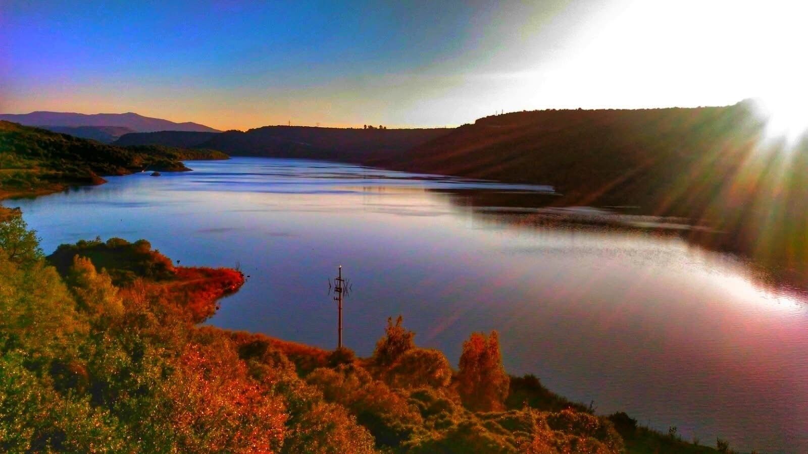 Un lago tranquilo con cielo despejado y montañas a lo lejos.
