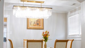 Un'area pranzo con un lampadario, un tavolo con un vaso di fiori e sedie.