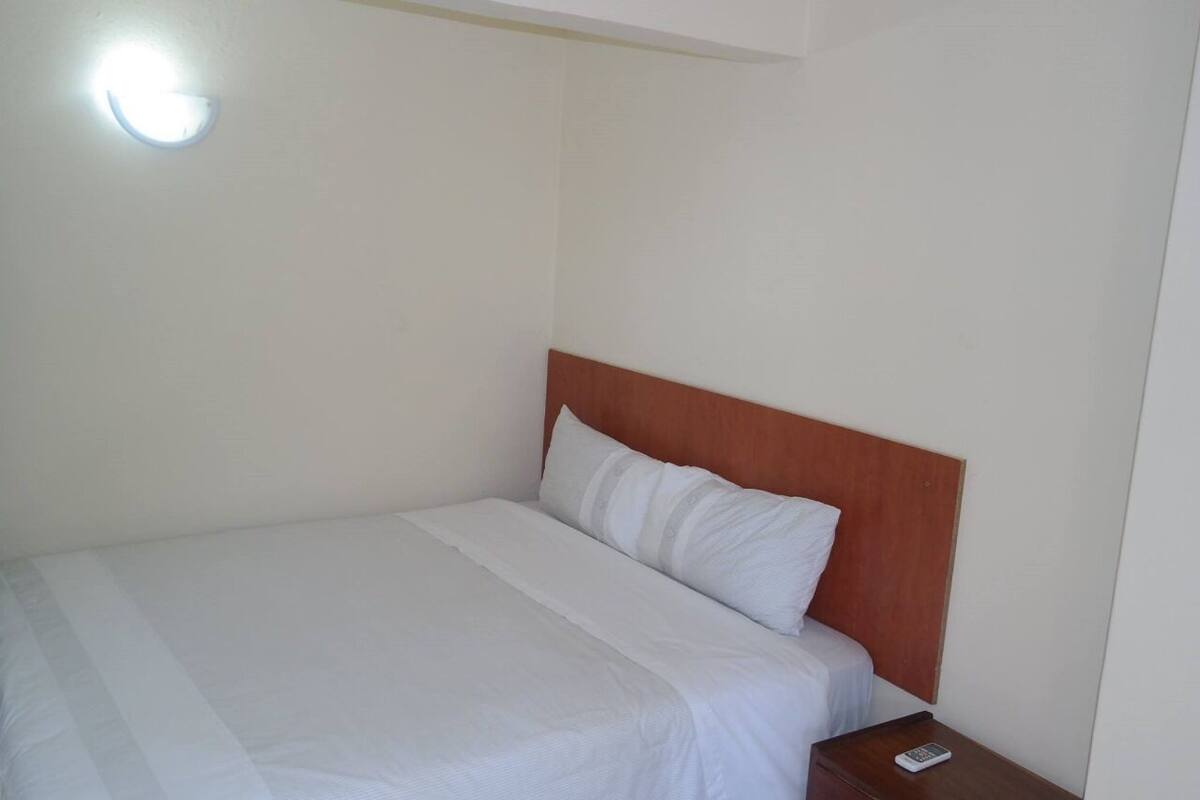 A single bed with a wooden headboard in a hotel room.