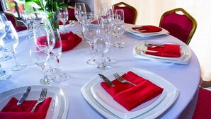 Una mesa de comedor preparada con varios vasos de vino, platos y servilletas rojas.