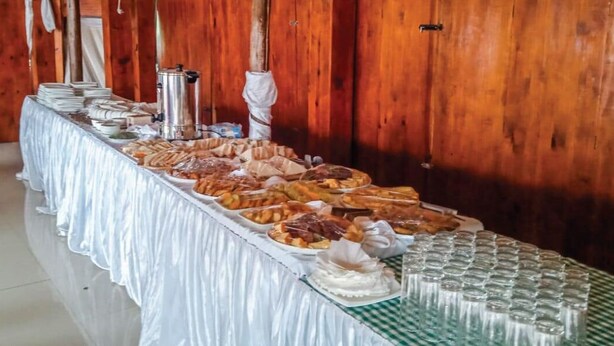 Una mesa de buffet con diversos alimentos y una estación de café en una sala con paredes de madera.