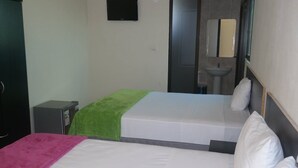 Habitación de hotel con dos camas, un escritorio pequeño, un espejo y un lavamanos.