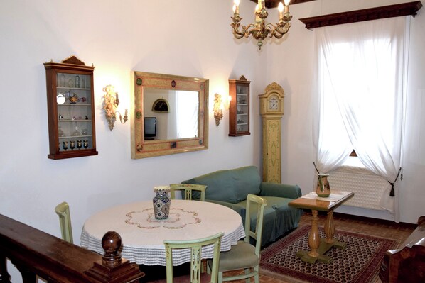 A dining area with a round table, chairs, a chandelier, and a clock.