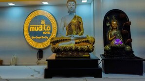 A Buddha statue in a meditative pose, a neon sign for Mudito Hotel, and a smaller Buddha statue with a water feature. - Mudita Hotel (West Kameng)