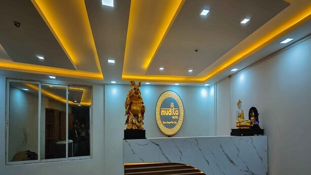 A hotel reception area with a marble counter, a statue, and a sign that reads "mudita HOTEL". - Mudita Hotel (West Kameng)