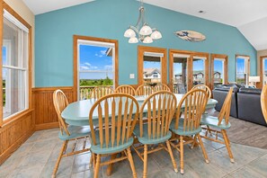 A dining area with a round table and chairs, large windows, and a view of the outside.