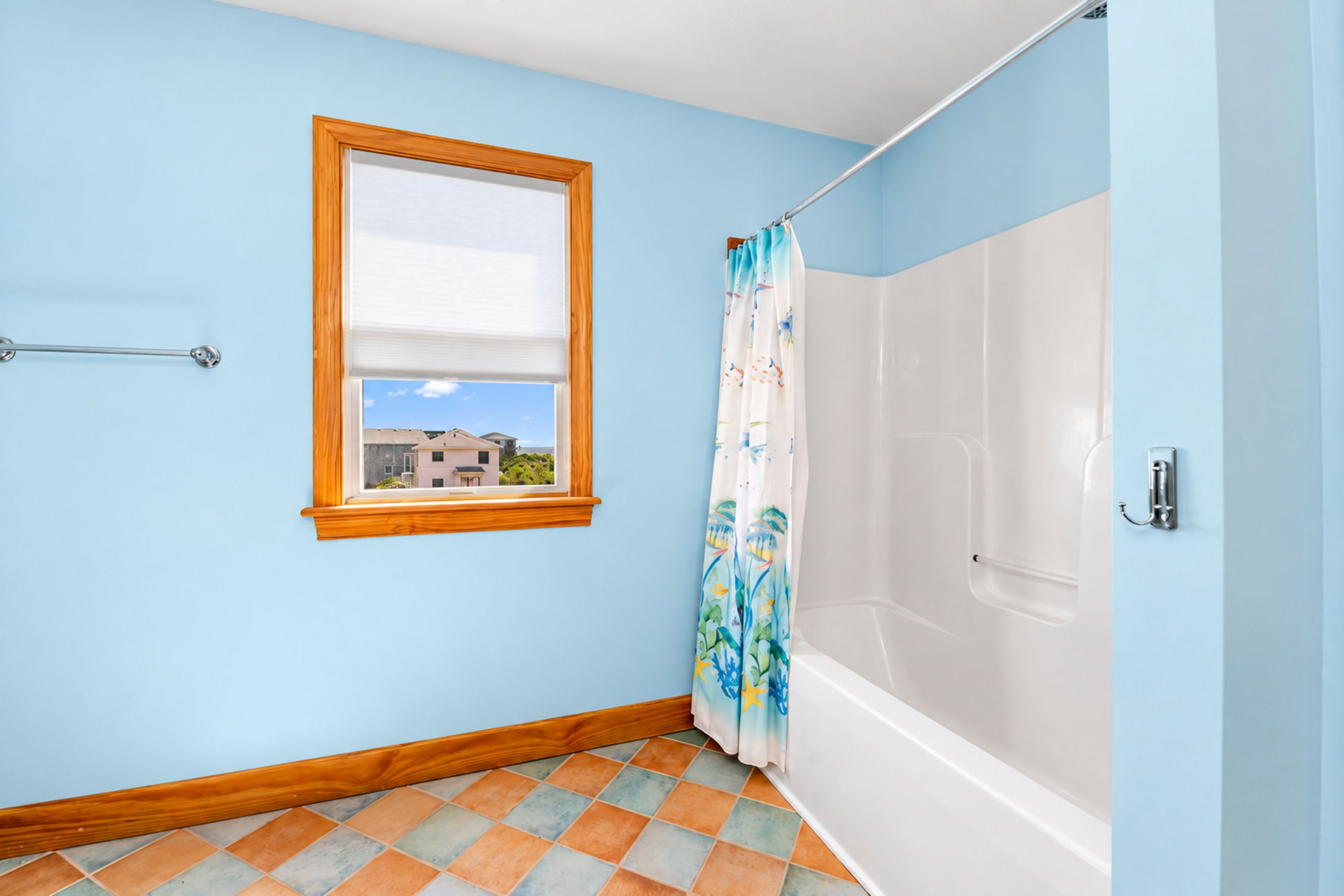 A bathroom with a window, a shower, and a tiled floor.