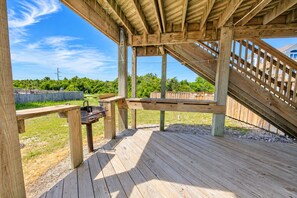 Une terrasse en bois avec un barbecue et un escalier menant à un niveau supérieur.