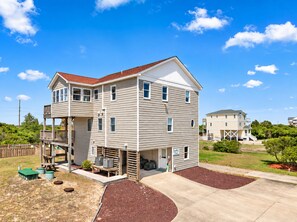A two-story residential building with a covered porch, a garage, and a landscaped yard. - 🏖 Ocean Views! 🌅Heated Pool, 🎯Game Room, 💦Hot Tub, Mini Golf & Steps to Sand (Nags Head)