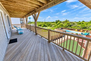 Une terrasse en bois avec une piscine, des chaises longues et une vue sur un paysage luxuriant.