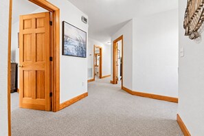 A hallway with wooden doors, a framed picture on the wall, and a light switch.