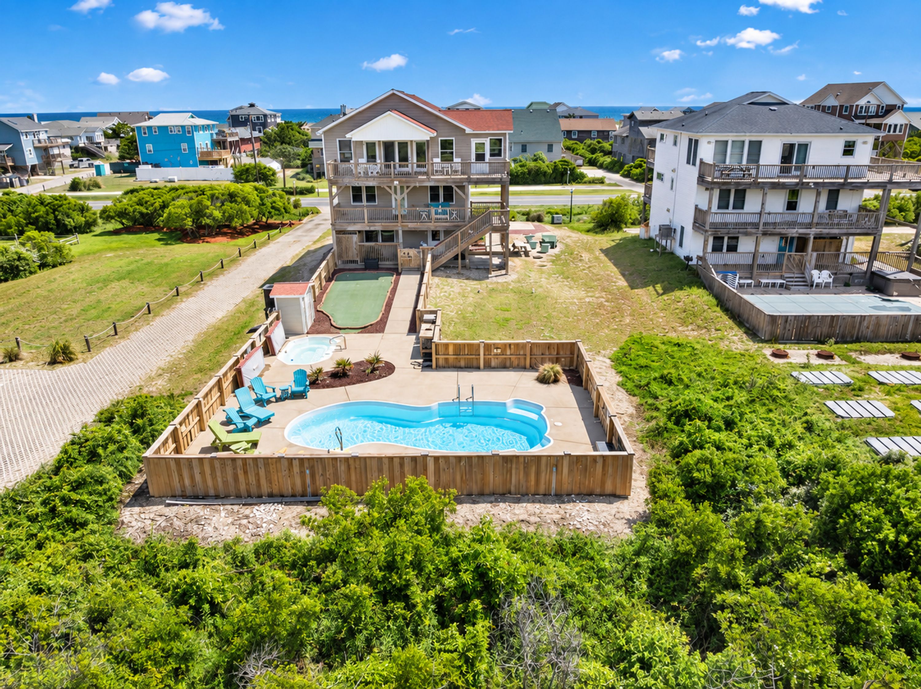 A residential area with a swimming pool, wooden deck, and multiple houses.