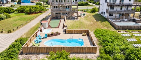 Zona residencial con piscina, terraza de madera y varias casas.