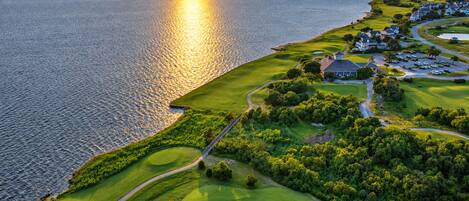 A golf course with a water body and residential area.