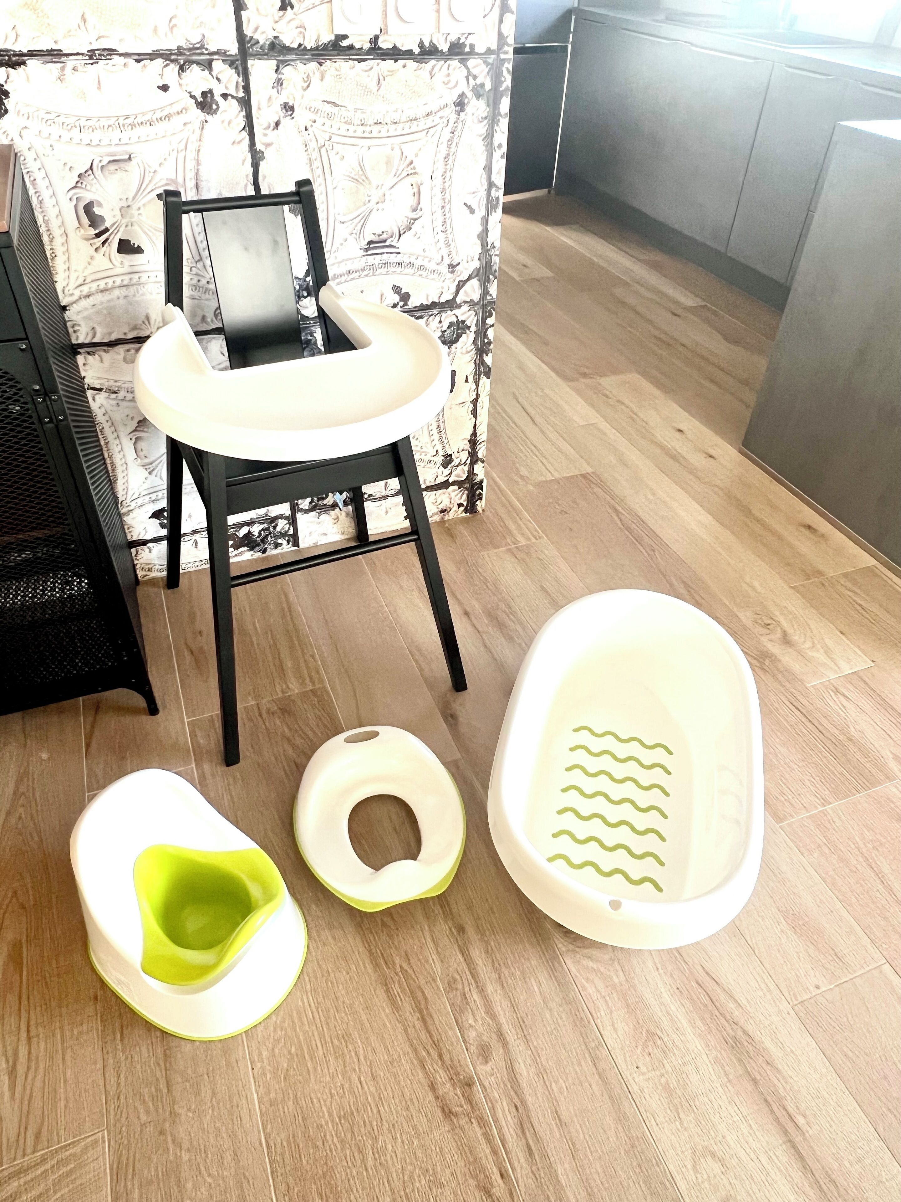 Une cuisine moderne avec un plancher en bois, une chaise noire et un table à langer blanche.