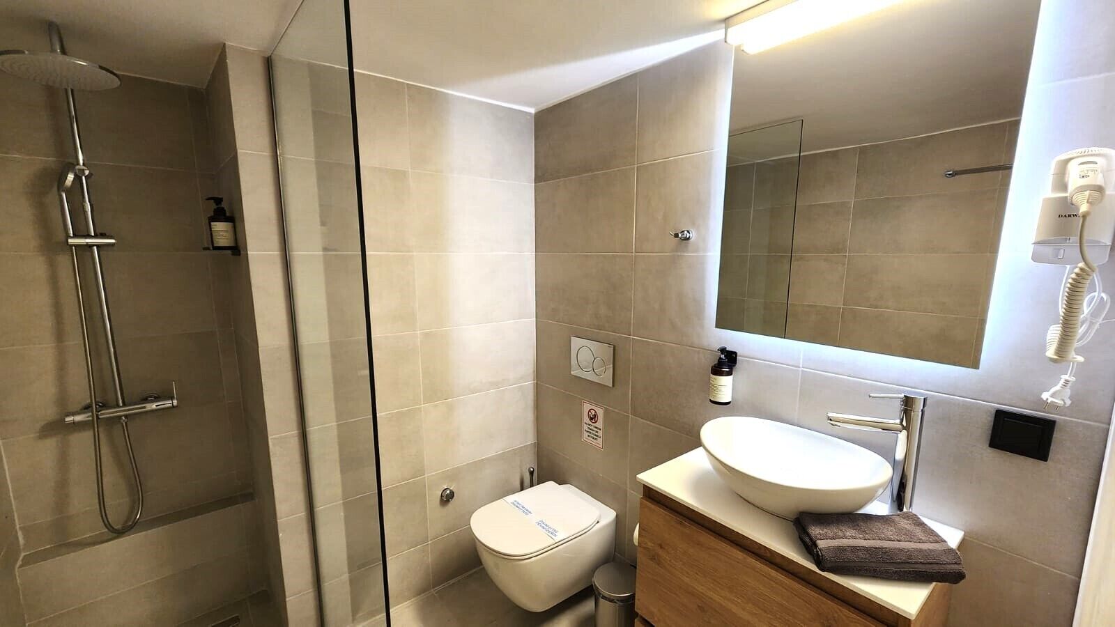A modern bathroom with a shower, toilet, and sink.
