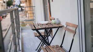 A balcony with a table, chairs, and a vase. - Grec Maison Piraeus by GrecCollection (Piraeus)