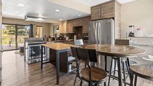 A modern kitchen with stainless steel appliances, a wooden dining table, and a view of the outdoors.