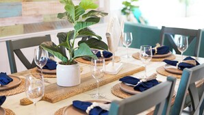 Een eettafel gedekt met borden, glazen en een bloempot.