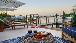 Een terras met loungezetels, een tafel met drankjes en uitzicht op het water.
