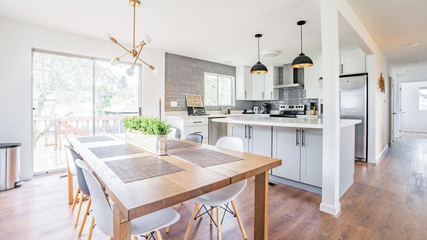Eine moderne Küche mit weißen Schränken, einem Holztisch und Pendelleuchten.