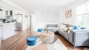 Ein modernes Wohnzimmer mit grauem Sofa, blauem Hocker und einem gewebten Korb.