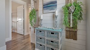 A hallway with a wooden floor, a white door, and a wall-mounted wicker basket unit. - B3 Sand Ranch: 4  BR, 3  BA House in Crystal Beach, Sleeps 14 (Crystal Beach)