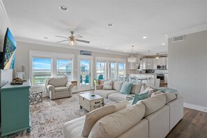 A spacious living room with a large sectional sofa, a coffee table, and a view of the ocean through large windows. - B3 Sand Ranch: 4  BR, 3  BA House in Crystal Beach, Sleeps 14 (Crystal Beach)