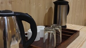 Ein Holztisch mit einem Wasserkocher, einer Glaskaraffe und einer Ablage mit Salz- und Pfefferstreuern.