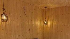 Ein Schlafzimmer mit Holzbalkendecke, einem Bett mit weißer Bettwäsche, zwei Nachttischen und hängenden Leuchten.