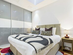 Une chambre moderne avec un grand lit, une table de chevet et une porte-fenêtre coulissante.
