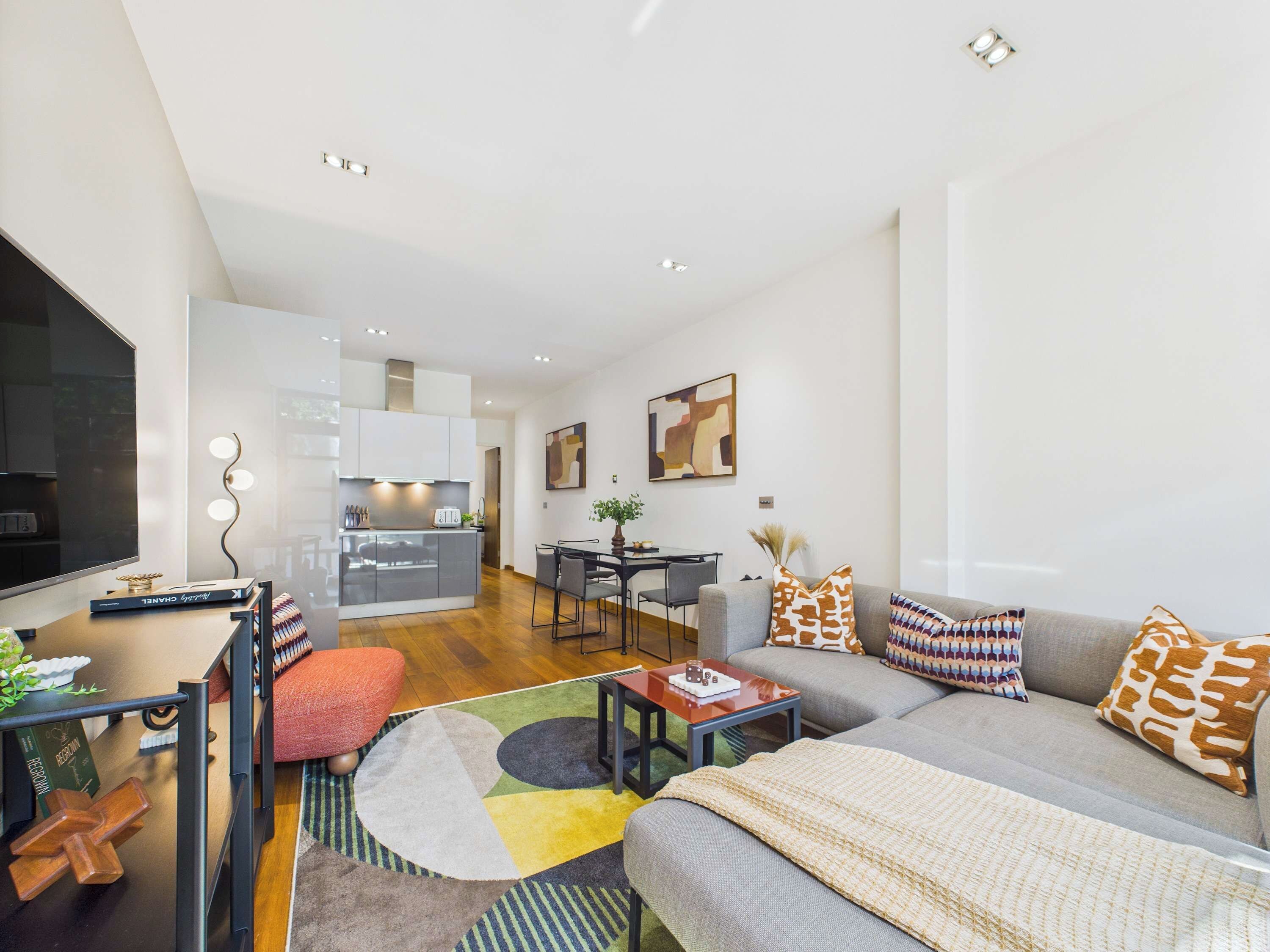 A modern living room with a sofa, coffee table, and a dining area with chairs.