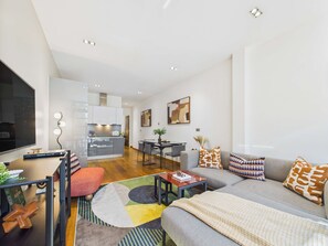 A modern living room with a sofa, coffee table, and a dining area with chairs.
